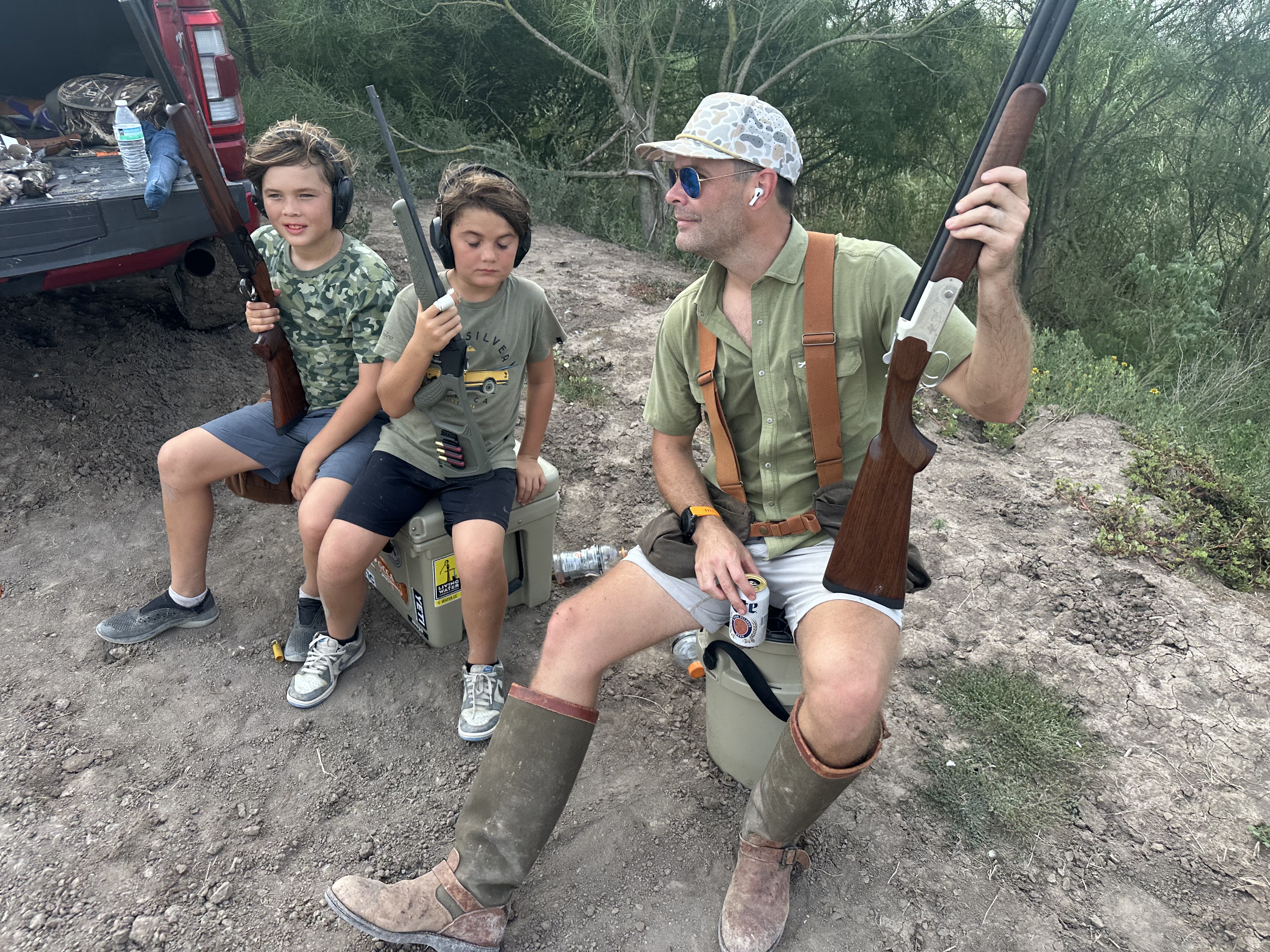Young hunters with shotguns alongside a guide in the field