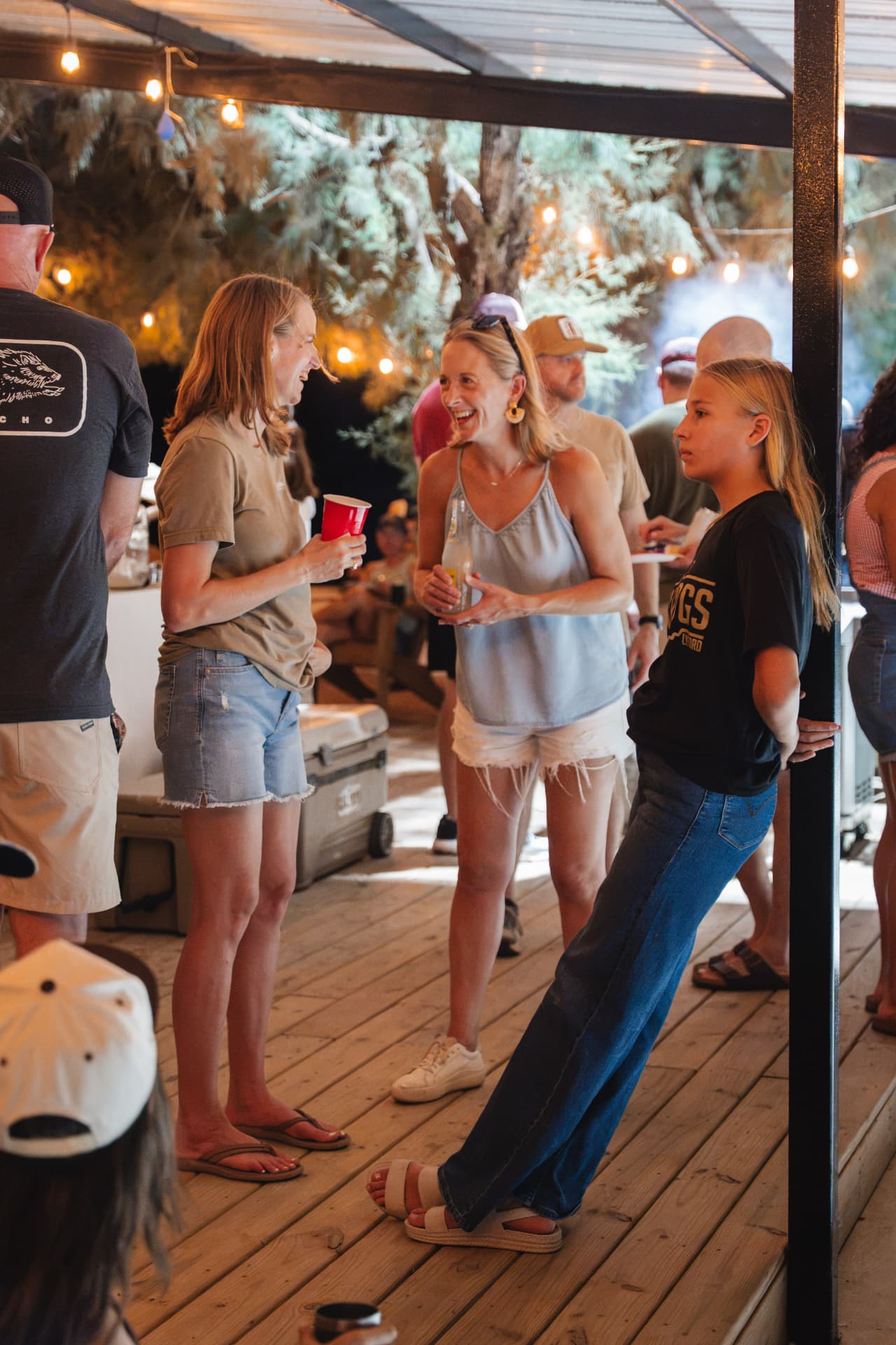 Friends laughing on the deck with cold drinks in hand