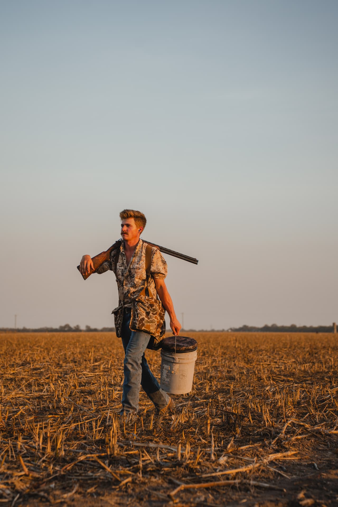 Walking out at sunset with gun and gear bucket