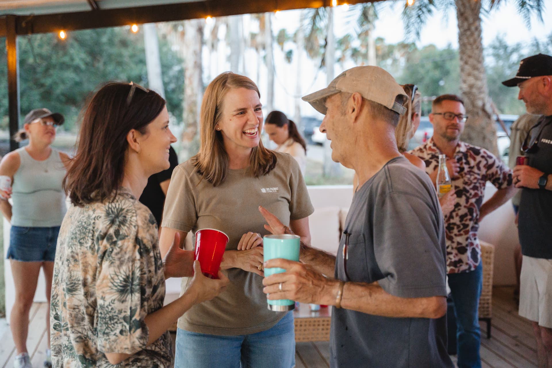 Guests laughing with drinks under the patio string lights