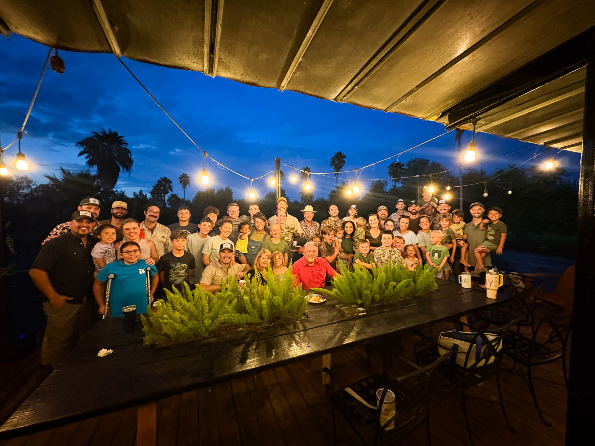 Full crew gathered under the string lights at dusk