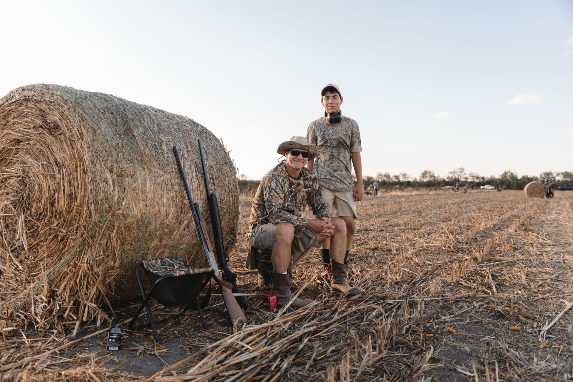Father and son resting by the round hay bale