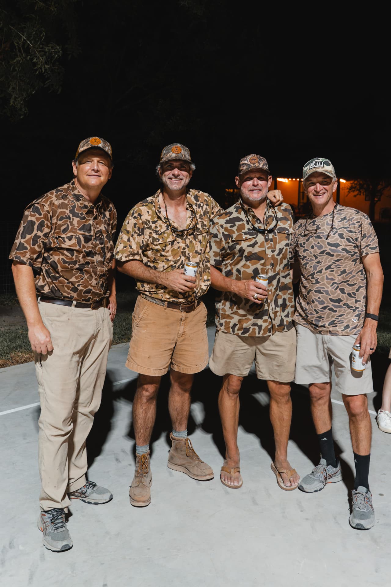 Four hunters in camo toasting with canned drinks