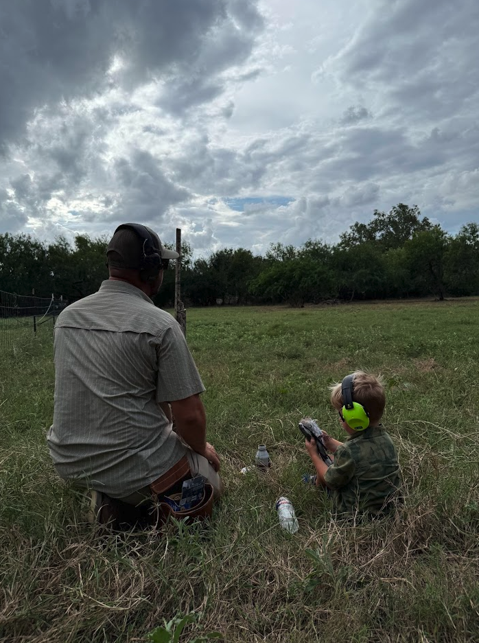 Adult and child seated in the field watching the sky