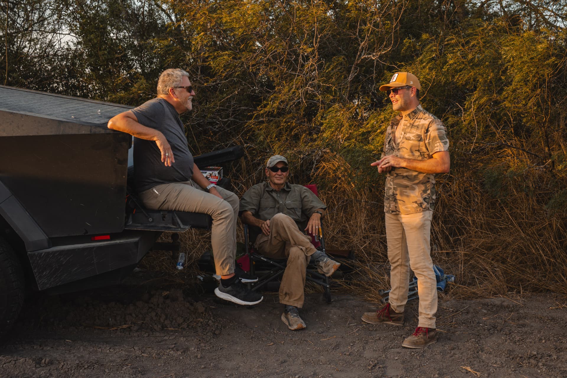 Hunters visiting in chairs on the tailgate along the tree line