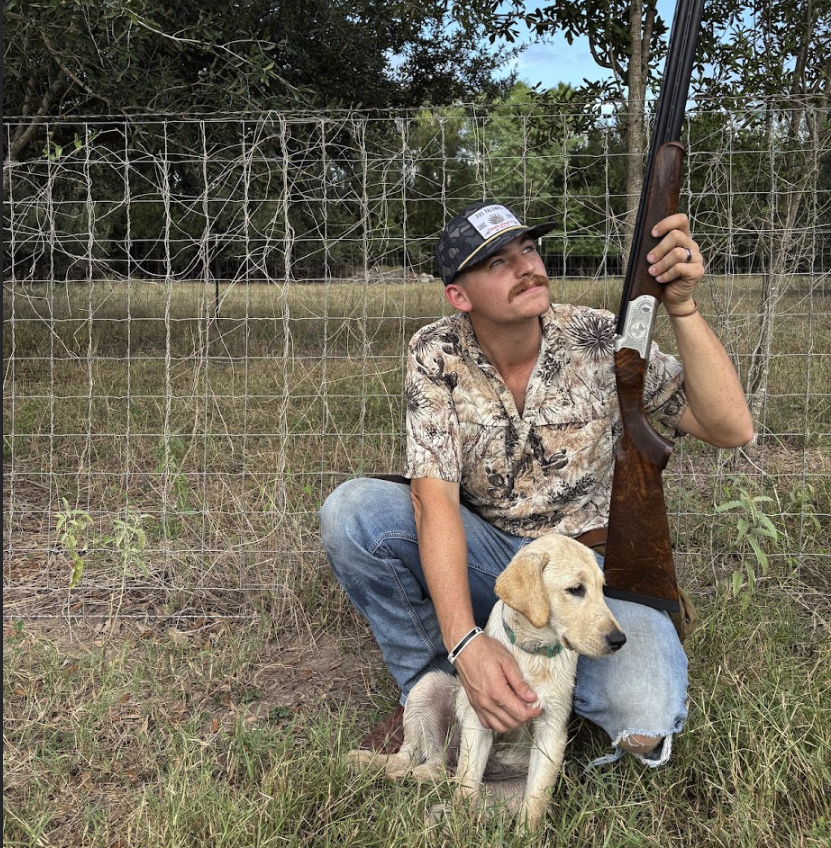 Hunter kneeling with his yellow lab and over-under shotgun