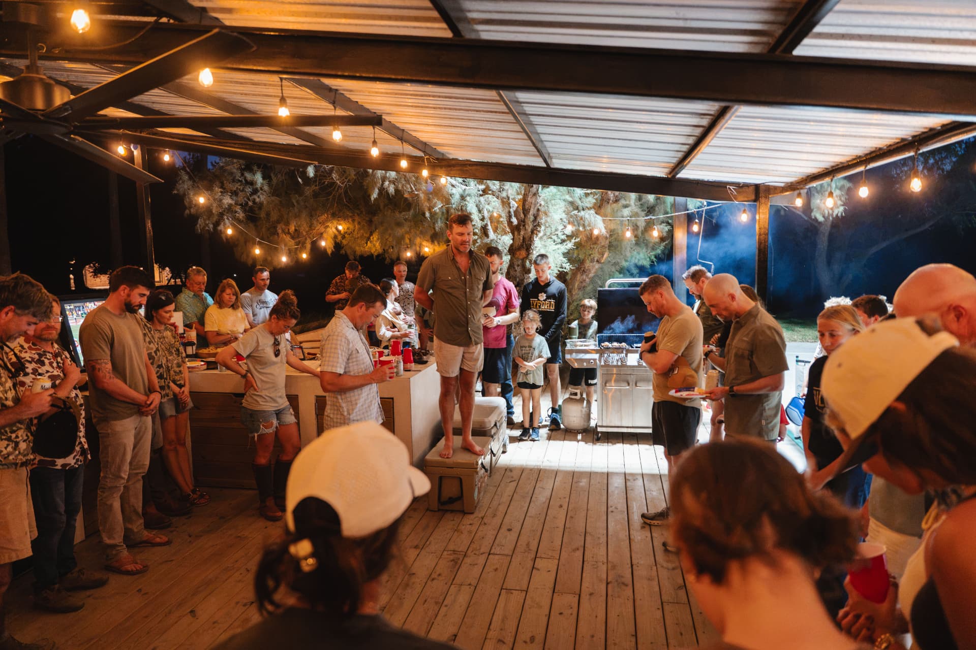 The group bowing heads in prayer beside the grill