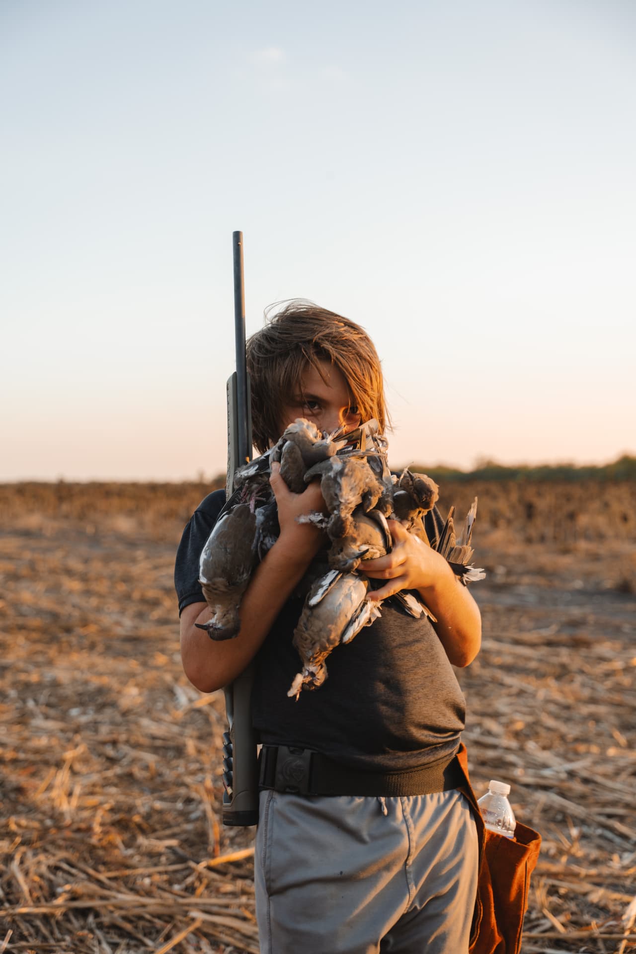 Young hunter heading in at sunset with an armful of doves