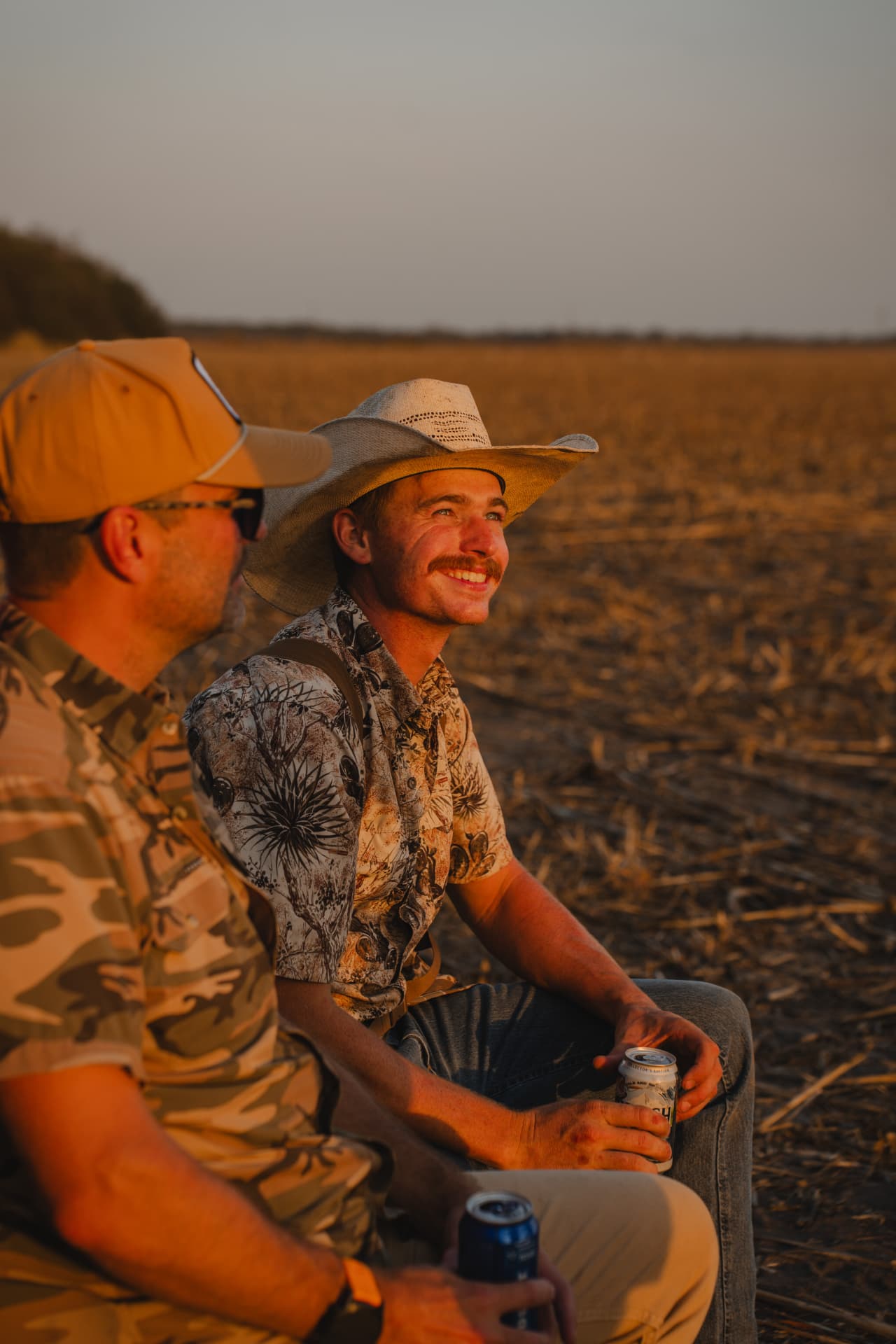Two hunters relaxing in the field at sunset