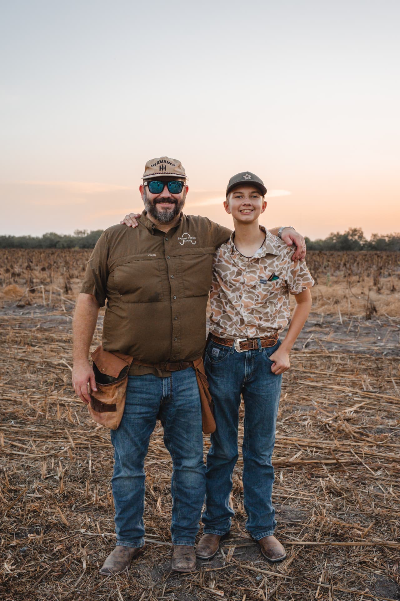 Father and son portrait in the sunflower fields at sunset