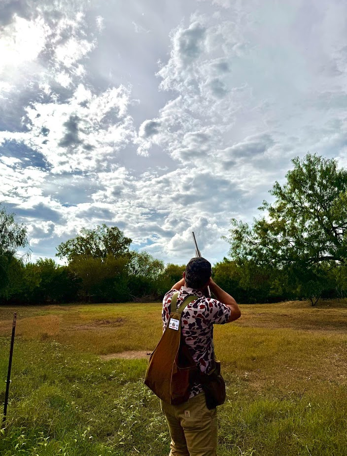 Hunter aiming into a wide South Texas sky